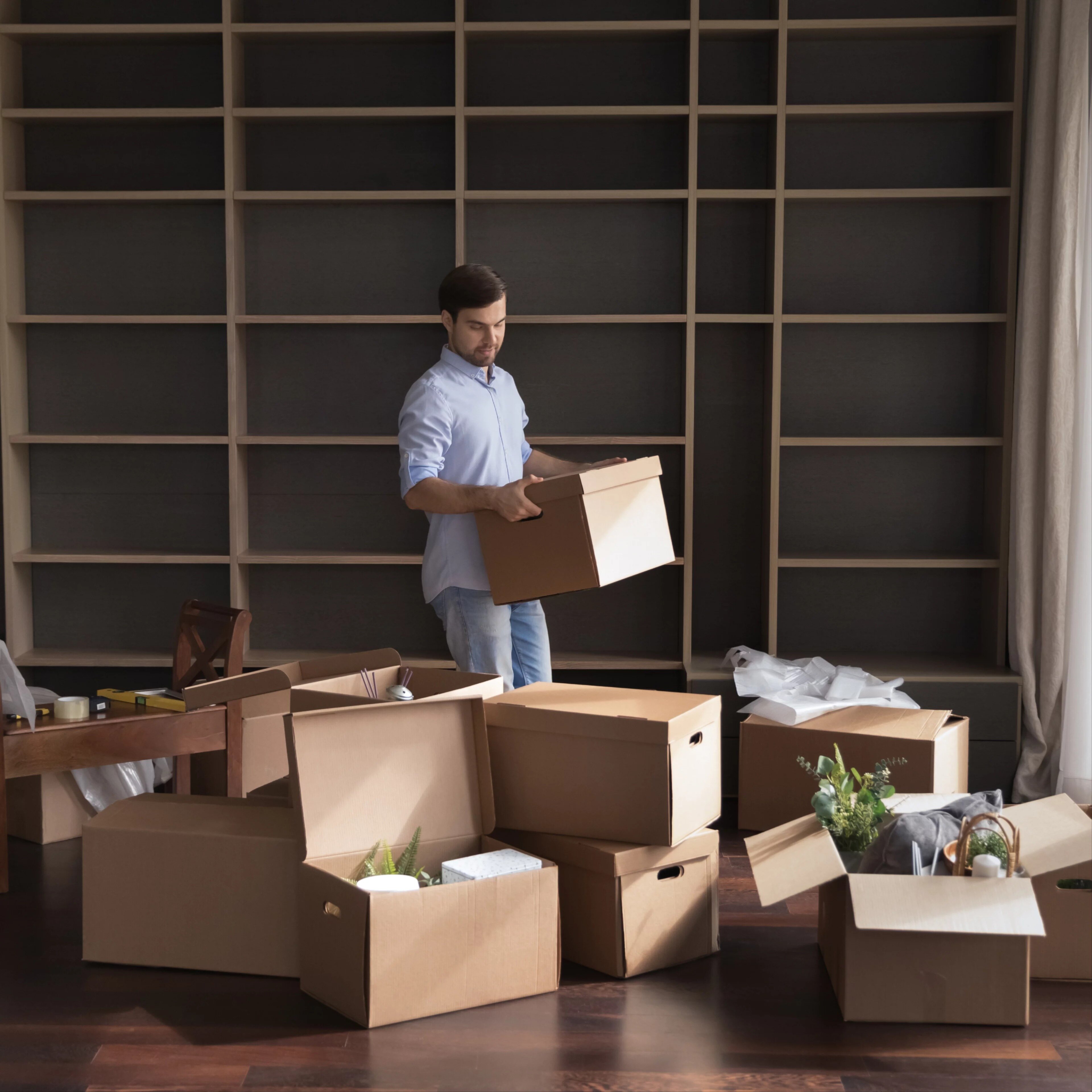 Homme portant des cartons dans un salon pendant une journée de déménagement.